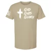 Sand-colored tee with a white painted cross icon and “God Guts Glory” mantra in bold script