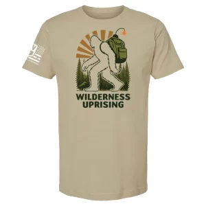 Sand t-shirt with Wilderness Uprising backpacking Bigfoot graphic, forest backdrop, sunburst, and text “Wilderness Uprising”